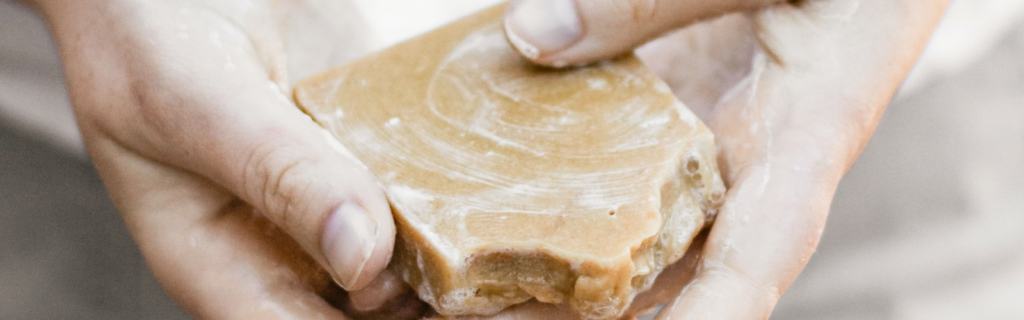 Hands holding a bar of soap with lathering visible on soap