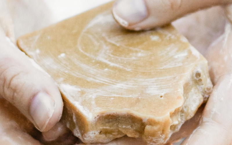 Hands holding a bar of soap with lathering visible on soap